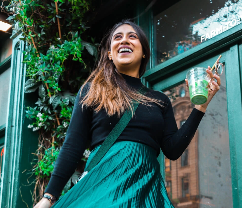 Laura Vargas smiling on a city street with a matcha latte