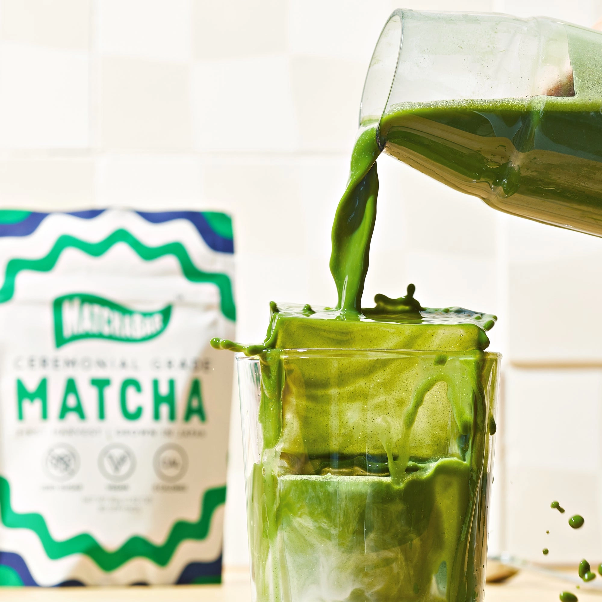 A glass of matcha latte on a wooden table beside a pouch
